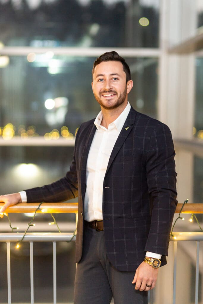 A man in suit and tie standing next to railing.